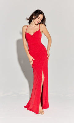 A woman barefoot stands against a plain light background, looking down and smiling in the Spaghetti-Strap Glitter Prom Gown: Eureka EK116 — a sleeveless, floor-length red formal dress featuring a thigh-high slit.