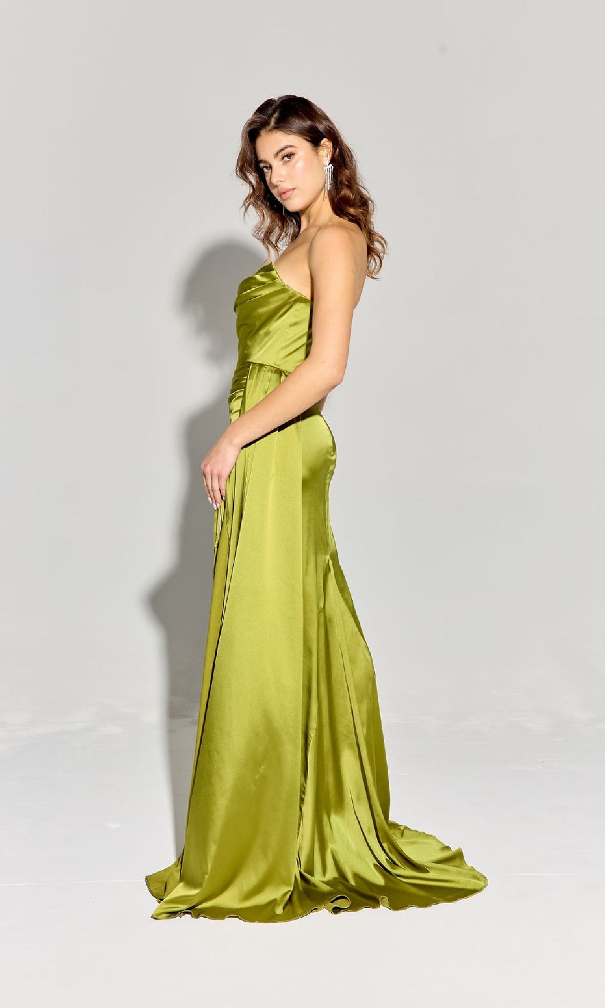 A woman stands in profile wearing the Eureka EK118 Strapless Long Satin Prom Dress in lime green, shown floor-length against a plain light gray background.