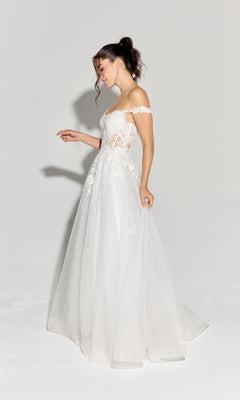 A woman in the Eureka EK128 Off-Shoulder Long Prom Ball Gown with a lace tulle skirt and corset bodice stands against a plain background, looking down with one arm slightly raised.