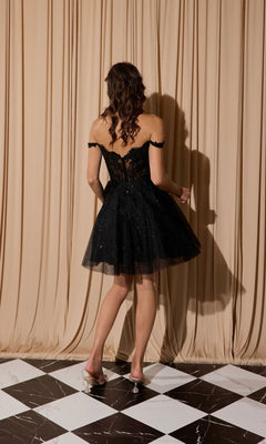 A woman with wavy hair faces a beige curtain, wearing the Short Glitter-Tulle Homecoming Dress: Eureka EK138 and transparent-heeled shoes on a black and white checkered floor.