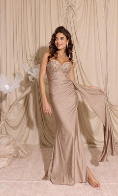 A woman stands barefoot on a light beige floor against draped beige fabric, wearing the Eureka EK166 Long Prom Dress in Biscuit—a strapless, fitted gown with shimmery fabric and a sheer-embroidered sweetheart bodice.