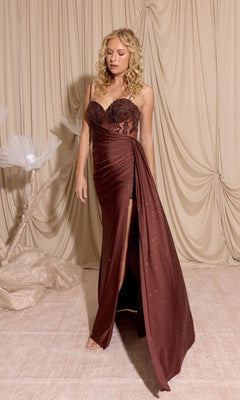 A woman with curly blonde hair wears the Eureka EK166 long prom dress in chocolate, featuring a strapless design, sheer-embroidered bodice, and thigh-high slit, standing before beige draped fabric.