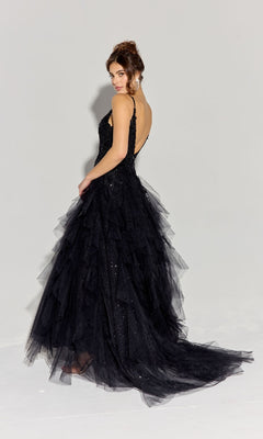 Woman wearing the Ruffled Long Glitter Prom Ball Gown: Eureka EK188—a sleeveless, floor-length black tulle dress with an open back and layered skirt—standing and looking over her shoulder against a plain light background.