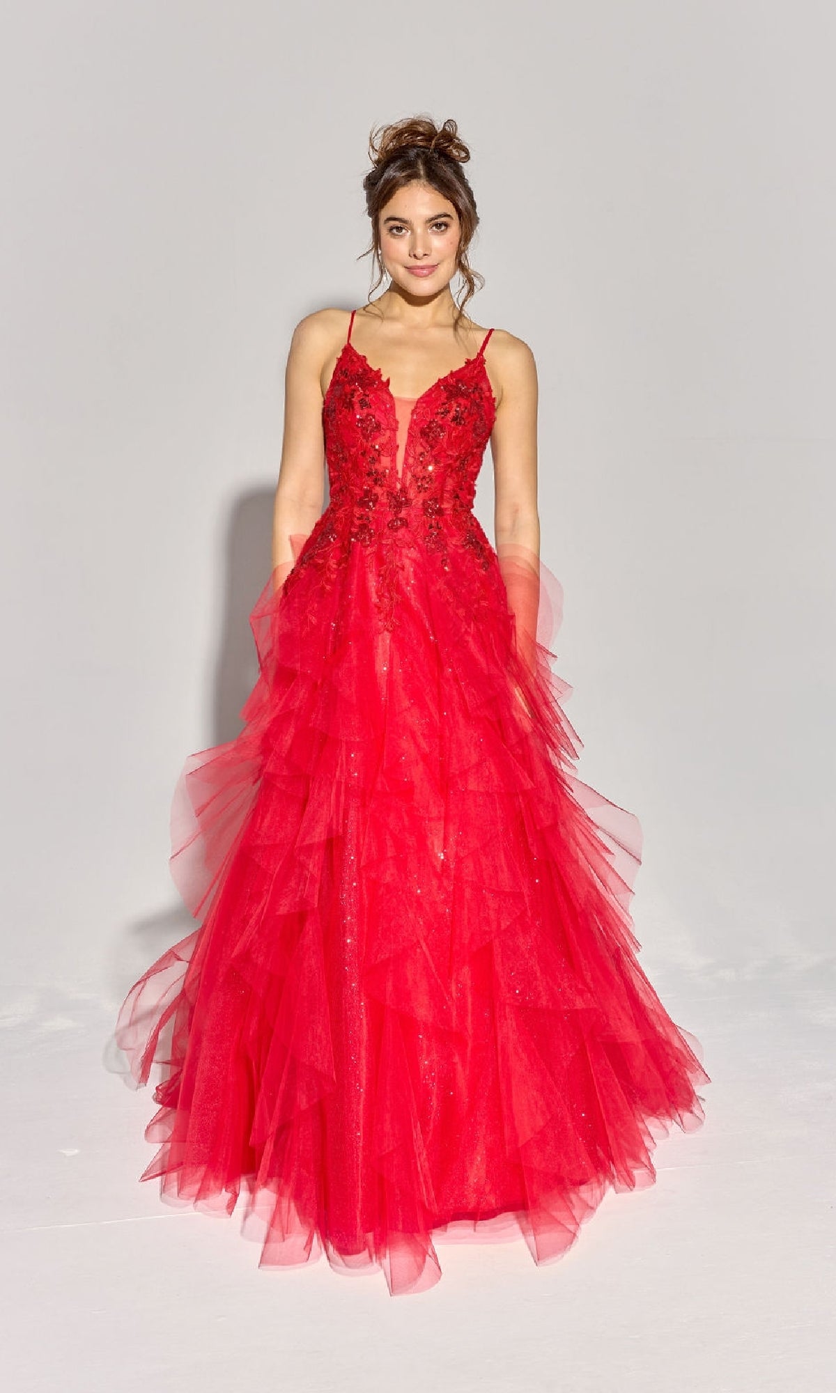 A woman poses against a plain background wearing the Eureka EK188 Ruffled Long Glitter Prom Ball Gown, a sleeveless, floor-length red dress with layered tulle and floral bodice embellishments.