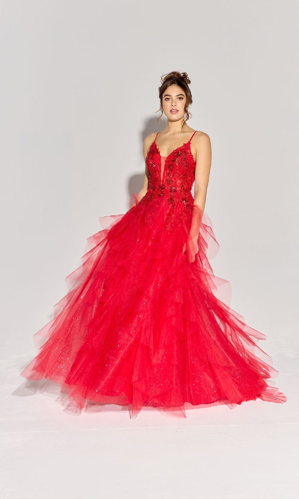 Woman poses in a studio wearing the Eureka EK188 Ruffled Long Glitter Prom Ball Gown, featuring a sparkling floor-length design with ruffled details, set against a plain light background.