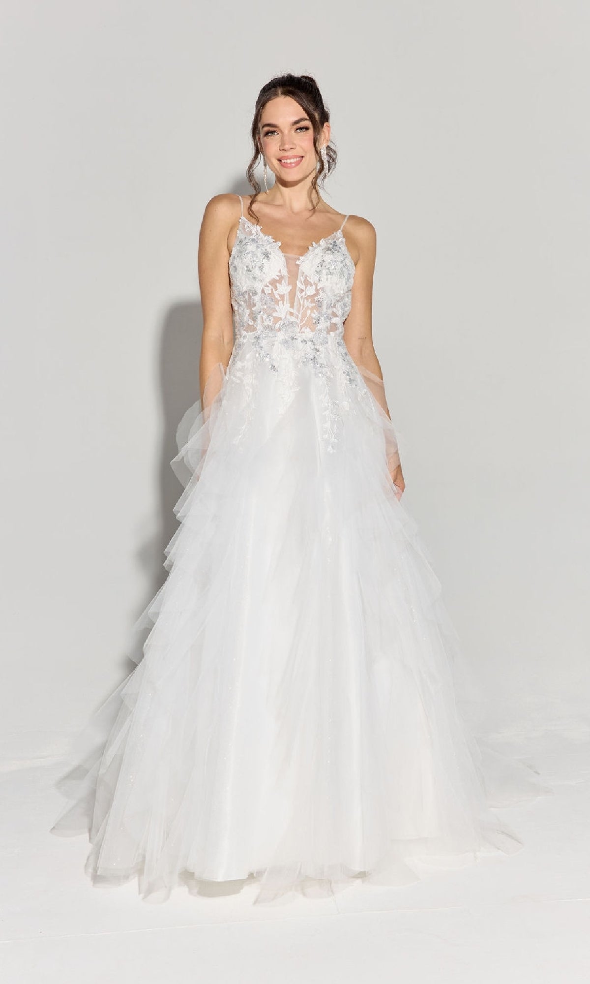 A woman stands smiling in the Eureka EK188 Ruffled Long Glitter Prom Ball Gown, a white, sleeveless, floor-length dress with a lace bodice and tulle skirt, set against a plain light background.