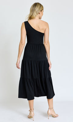 A woman faces away, wearing the One-Shoulder Casual Everyday Midi Dress in black with tiered midi layers and nude heels, set against a plain white background.