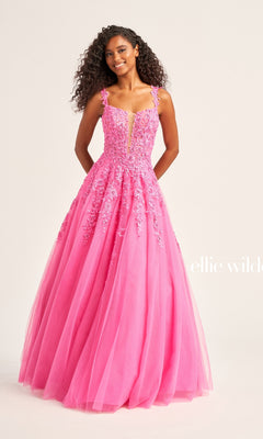 A woman in the Ellie Wilde EW120014 long glitter prom ball gown with floral appliqué details and a tulle skirt stands against a plain light background.