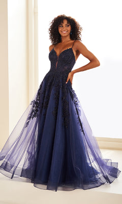 A woman stands indoors, smiling in the Sheer-Corset Long Lace Prom Ball Gown EW34036—a sleeveless deep navy dress with a fitted bodice, beaded accents, and a tulle skirt.