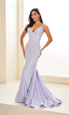A woman stands indoors near a window wearing the Ellie Wilde Long Designer Prom Dress EW35002, a fitted, light purple, sleeveless mermaid gown with a sweetheart neckline.