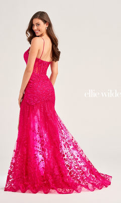 Woman wearing the Ellie Wilde Long Lace Mermaid Prom Dress EW35005 in bright pink with thin straps, looking over her shoulder and smiling against a plain background.