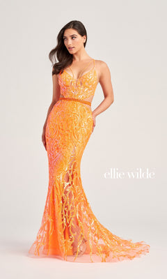 A woman stands against a plain light background in the Ellie Wilde Cut-Out Long Sequin Prom Dress EW35007, a fitted, floor-length formal gown with orange and gold sequins, a sheer bodice, and spaghetti straps. The "Ellie Wilde" logo is visible.
