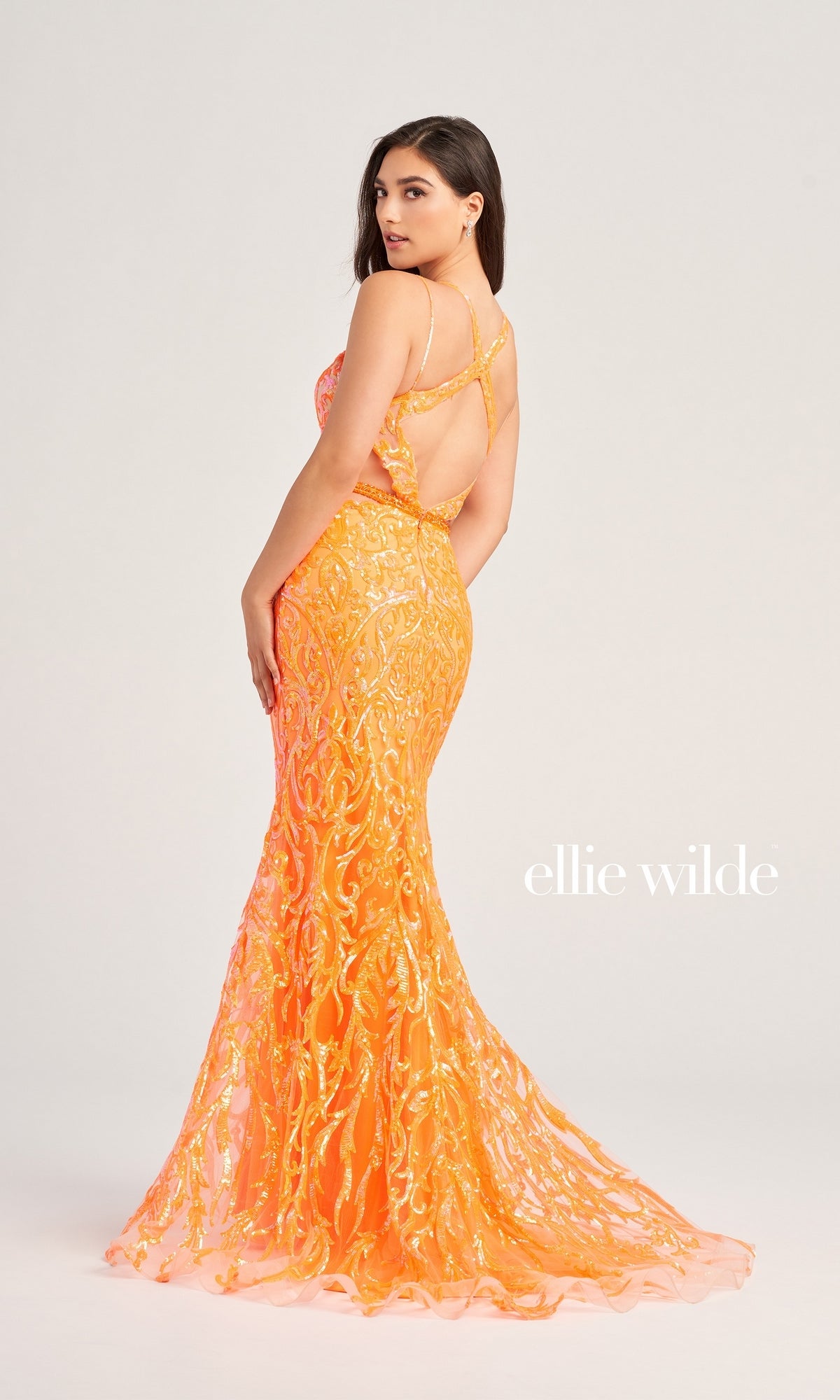 A woman poses in the Ellie Wilde Cut-Out Long Sequin Prom Dress EW35007, a fitted floor-length gown with orange and gold sequins, thin straps, cut-out sides, and an open back. The text 