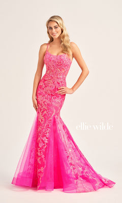 A woman poses with one hand on her hip, wearing the Ellie Wilde Sequin Long Mermaid Prom Dress EW35008—a fitted, bright pink floral lace sequin gown with thin straps—against a plain background. "ellie wilde" text appears on the image.
