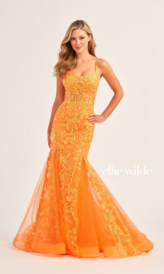 A woman wears the fitted Ellie Wilde Sequin Long Mermaid Prom Dress EW35008, a bright orange mermaid gown with floral embroidery, standing against a plain background. "ellie wilde" is displayed next to her.
