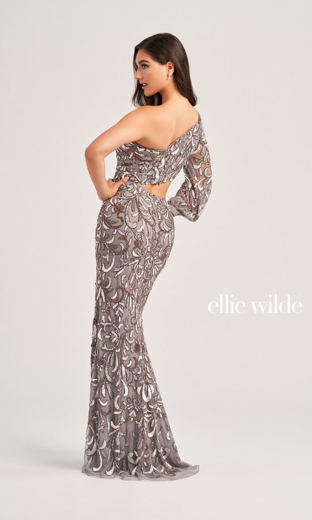 Woman models the One-Sleeve Ellie Wilde Beaded Formal Dress EW35020 in a side pose against a plain backdrop. 
