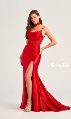 A woman wears the Ellie Wilde Choker Designer Prom Dress EW35028—a fitted red gown with a corset back, lace detailing, high slit, train, and stunning beaded-lace floral appliques for an elegant touch—standing against a plain background.