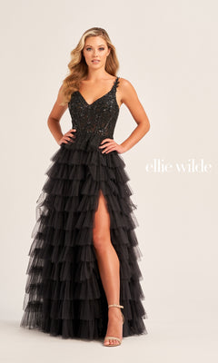 A woman poses in the Tiered Ellie Wilde EW35059 Designer Ball Gown, a black prom dress with a sequin corset bodice, ruffled tiered skirt, and high leg slit. "ellie wilde" appears in white text on the light beige background.