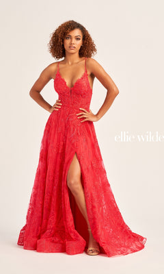 A woman poses confidently in the Ellie Wilde A-Line Long Glitter Prom Dress EW35103, featuring red embroidery and a front slit, against a plain background. The text "Ellie Wilde" is partially visible.