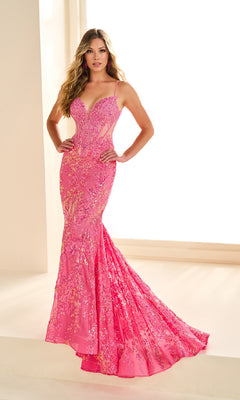 A woman stands indoors wearing the Ellie Wilde EW36003 Sequin-Print Mermaid Prom Dress, featuring a fitted floor-length silhouette, sheer corset bodice, and flared train.