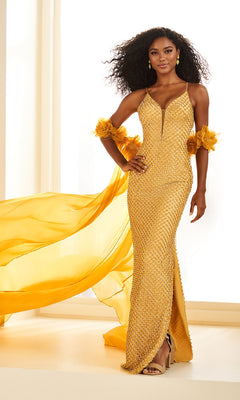 A woman wears the Ellie Wilde EW36027 long prom dress—a fitted gold beaded mesh gown with thin straps, high slit, ruffled wrist details, matching gold earrings, and a detachable floor-length cape flowing behind her.