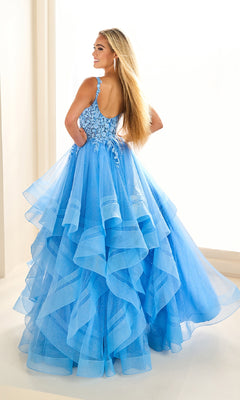 A woman stands with her back turned, wearing the Ellie Wilde EW36035 long glitter prom ball gown featuring floral bodice detailing and a sheer tulle skirt.