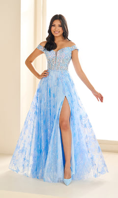 A woman stands indoors, smiling in the Ellie Wilde EW36039 glow-in-the-dark prom dress—a light blue off-the-shoulder gown with a floral corset bodice, high leg slit, and matching heels.