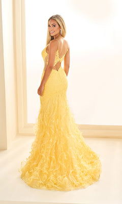 A woman looks over her shoulder wearing the Ellie Wilde EW36041 long prom dress, a yellow lace mermaid gown with an open back, ruffled train, and elegant v-neckline.