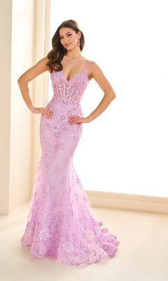 Woman poses indoors in the fitted, floor-length lavender Ellie Wilde EW36082 prom dress featuring a mermaid silhouette, floral lace details, embroidered glitter tulle accents, and thin straps.