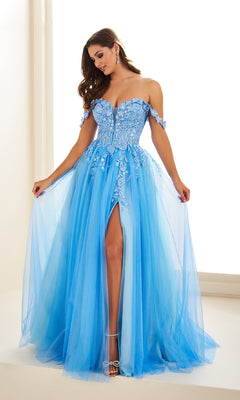 A woman poses indoors in the Ellie Wilde EW36214, a long off-the-shoulder light blue tulle prom dress featuring an A-line silhouette, floral lace applique corset bodice, and a thigh-high slit.