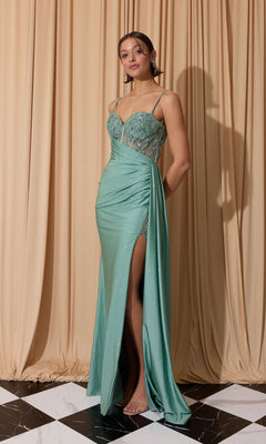 A woman stands on a black and white tiled floor in the Eureka EK166 long prom dress, featuring light green fabric, lace detailing, a sheer embroidered bodice, thigh-high slit, draped skirt, and beige curtains in the background.