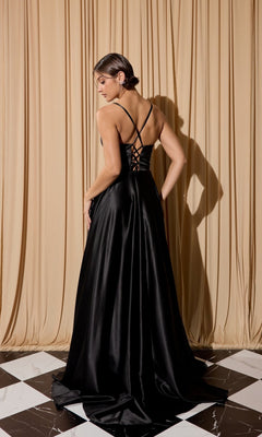 A woman wearing the Eureka EK190 long prom dress in black satin with an open back and lace-up detail stands on a checkered floor before beige drapes, facing away from the camera.