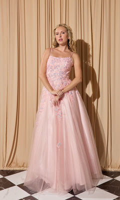 A woman stands in front of beige curtains wearing the Eureka EK197 long prom dress in pink, featuring thin straps and delicate floral embellishments.