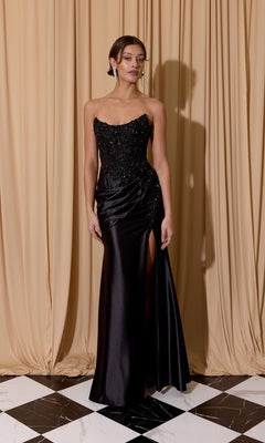 A woman poses on a black-and-white floor in front of beige curtains, wearing the Eureka EK202 long prom dress with a strapless beaded bodice, satin sheath skirt, and thigh-high slit. Her hair is pinned back.