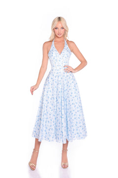 Woman poses in the Eliza Light Blue Floral Halter Summer Midi Dress with a corset bodice and beige heels against a white background.