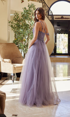 A woman in the Nox Anabel F1567 Asymmetrical Glitter Prom Dress stands in a bright, elegant room with marble floors, a grand staircase, and a large plant in the background.