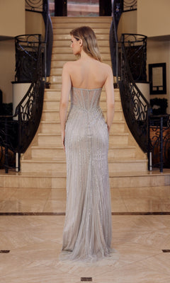 A woman wearing the Nox Anabel F1569 Strapless Long Sequin Prom Dress stands with her back to the camera, highlighting the shimmering gown in front of a grand staircase.