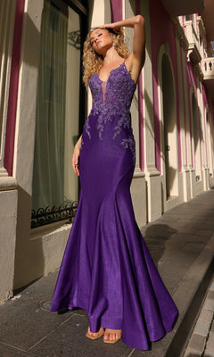 A woman wears the Lace-Up Embroidered Bodice Long Prom Dress G1364, a sleeveless, floor-length gown with beaded lace, standing on a sidewalk beside a pink and cream building.