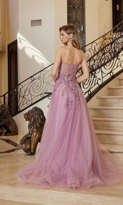 A woman in the Nox Anabel G1371 Strapless Long Prom Ball Gown poses on a marble staircase beside bronze lion statues, showcasing the elegant floor-length pink dress with lace embroidery and floral details.