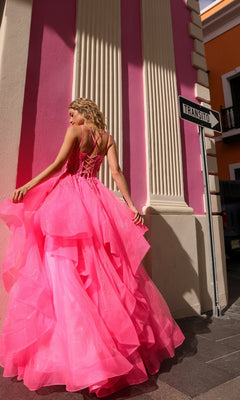 A woman in the Lace-Up Long Tiered Prom Ball Gown H1351, a bright pink dress with tulle ruffles, stands near a "Transito" street sign with colorful buildings in the background.