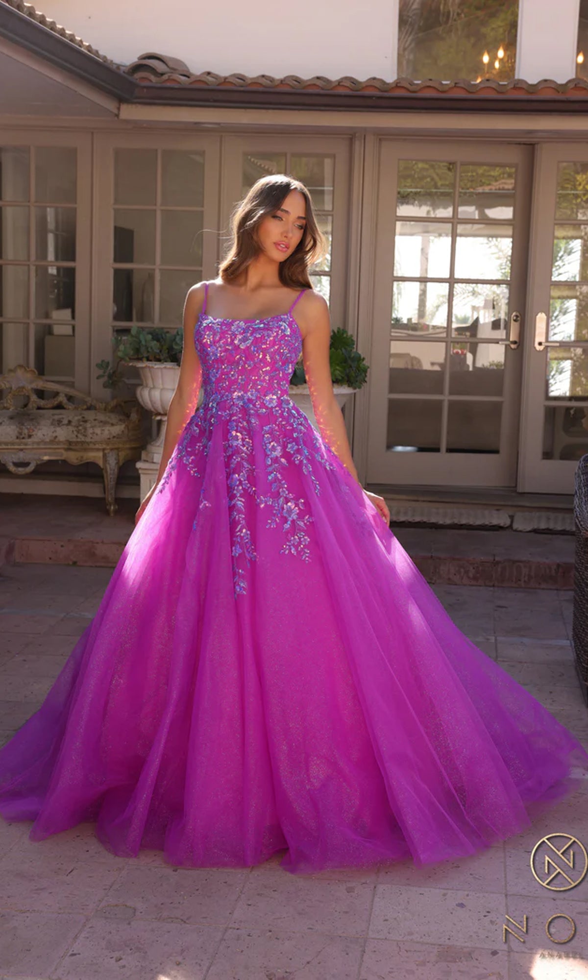 A young woman stands outside in front of glass doors, wearing the Embellished Hunter Green Long Prom Ball Gown H1464, a floor-length ball gown with floral embellishments on the bodice and skirt.