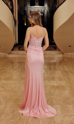 A woman stands indoors on marble flooring, facing away from the camera, wearing the Nox Anabel H1671 Glitter-Corset Long Prom Dress in light pink.