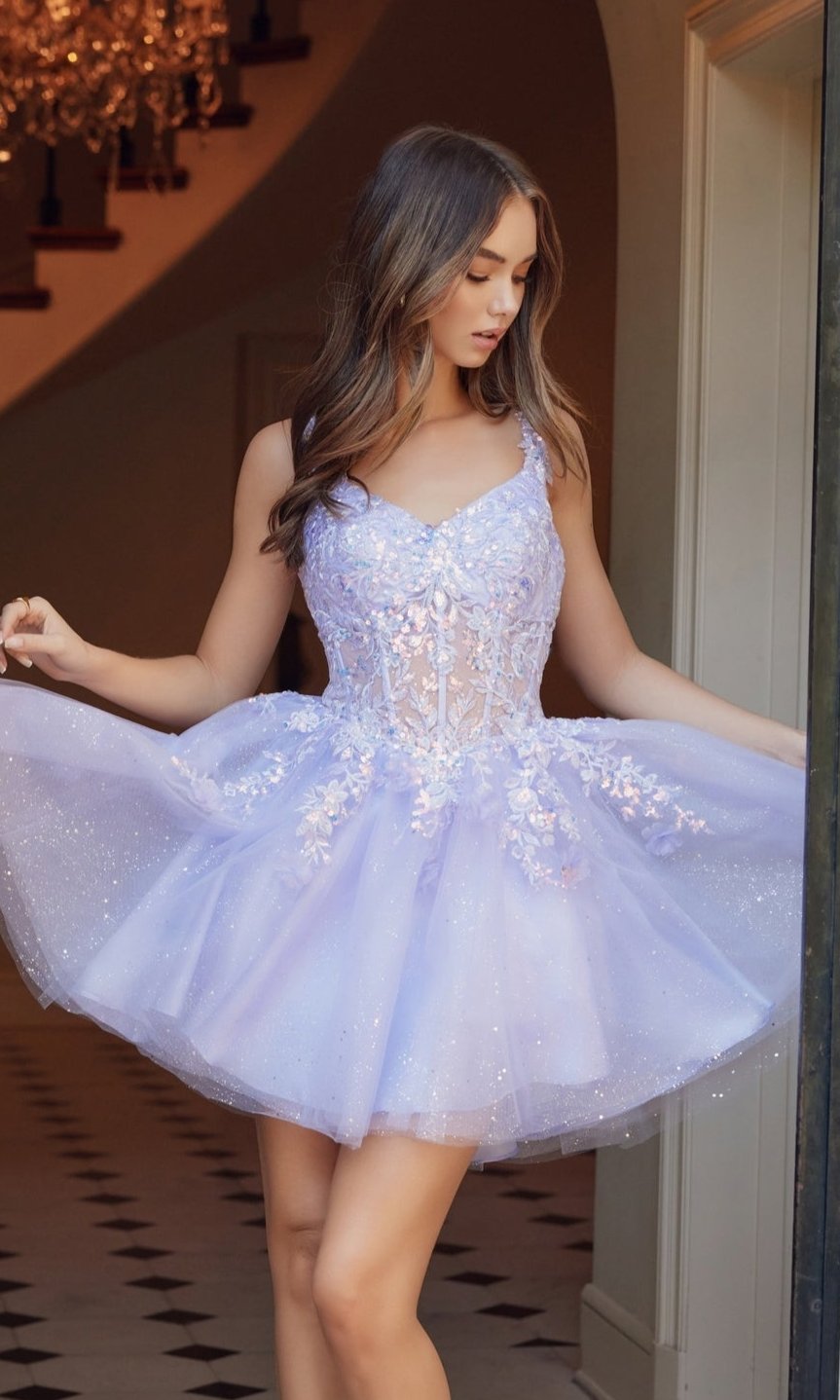 A woman poses indoors in the Embroidered-Bodice Short A-Line Hoco Dress H846—a light purple, sparkly dress with floral embellishments, a flared tulle skirt, and an embroidered-lace sweetheart bodice.