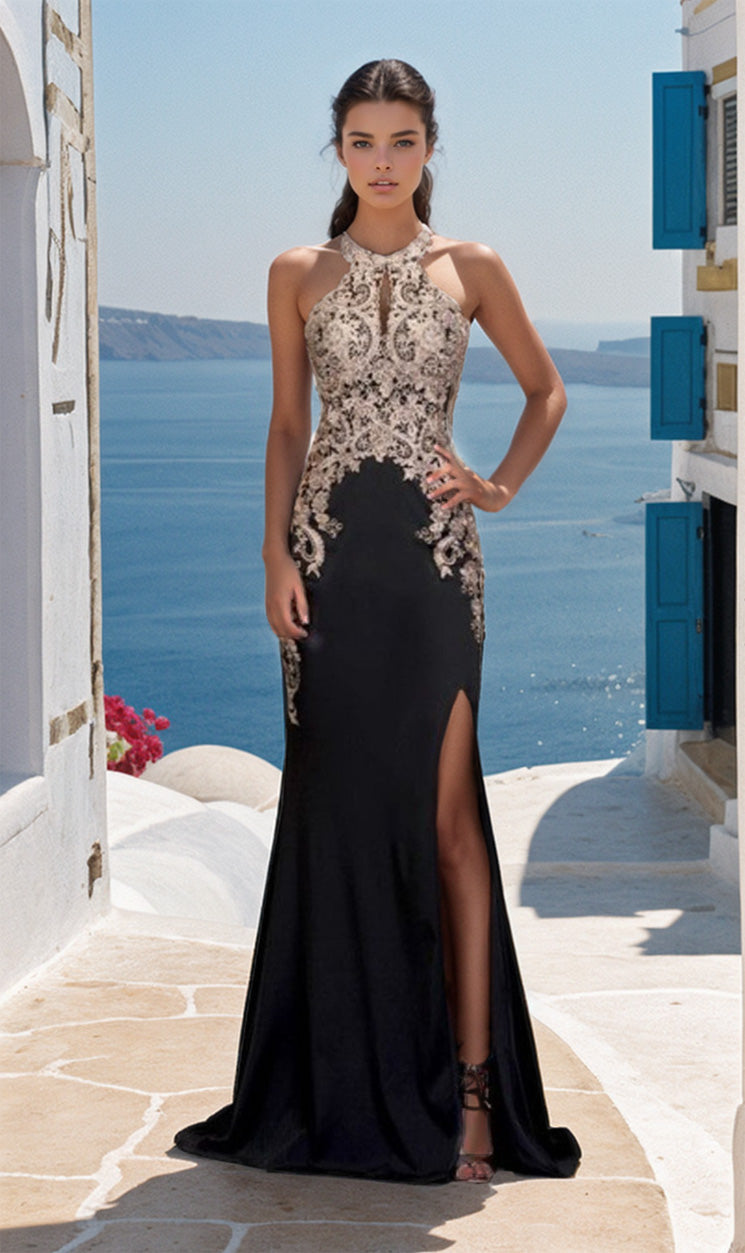 A woman stands by the sea in the Sheer Illusion-Sides Long Prom Dress: Chicas C1541, a sleeveless high-neck gown with gold embroidered lace and a thigh-high slit. White buildings with blue shutters appear in the background.