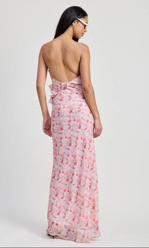 A woman with long dark hair models the Pink Floral Backless Summer Maxi Dress, featuring thin straps and an open back, against a plain light background.