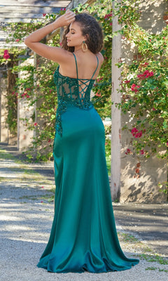A woman in the Velvi Lace-Up Sheer-Corset Long Prom Dress Ivy, a long emerald green gown with satin fabric and beaded details, stands outdoors facing away with one arm raised.