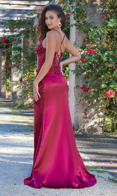 A woman stands outdoors in the Velvi Lace-Up Sheer-Corset Long Prom Dress Ivy, a fitted magenta gown with a floor-length skirt, corset bodice, and lace-up back, looking over her shoulder with roses and greenery behind her.