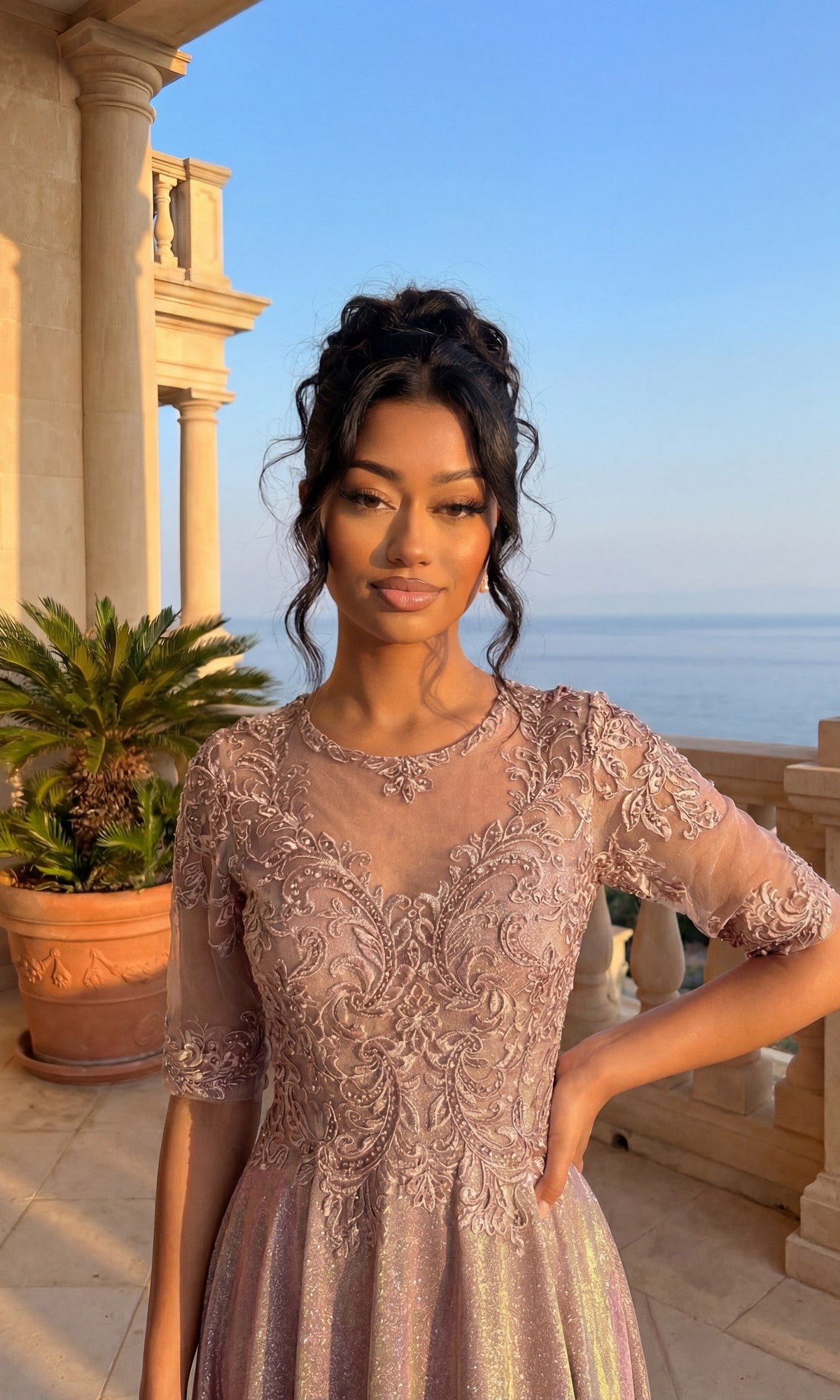 A woman in the Long Formal Dress: Chicas J006 stands on a sunlit balcony with stone columns, a potted palm, and a scenic sea view behind her.