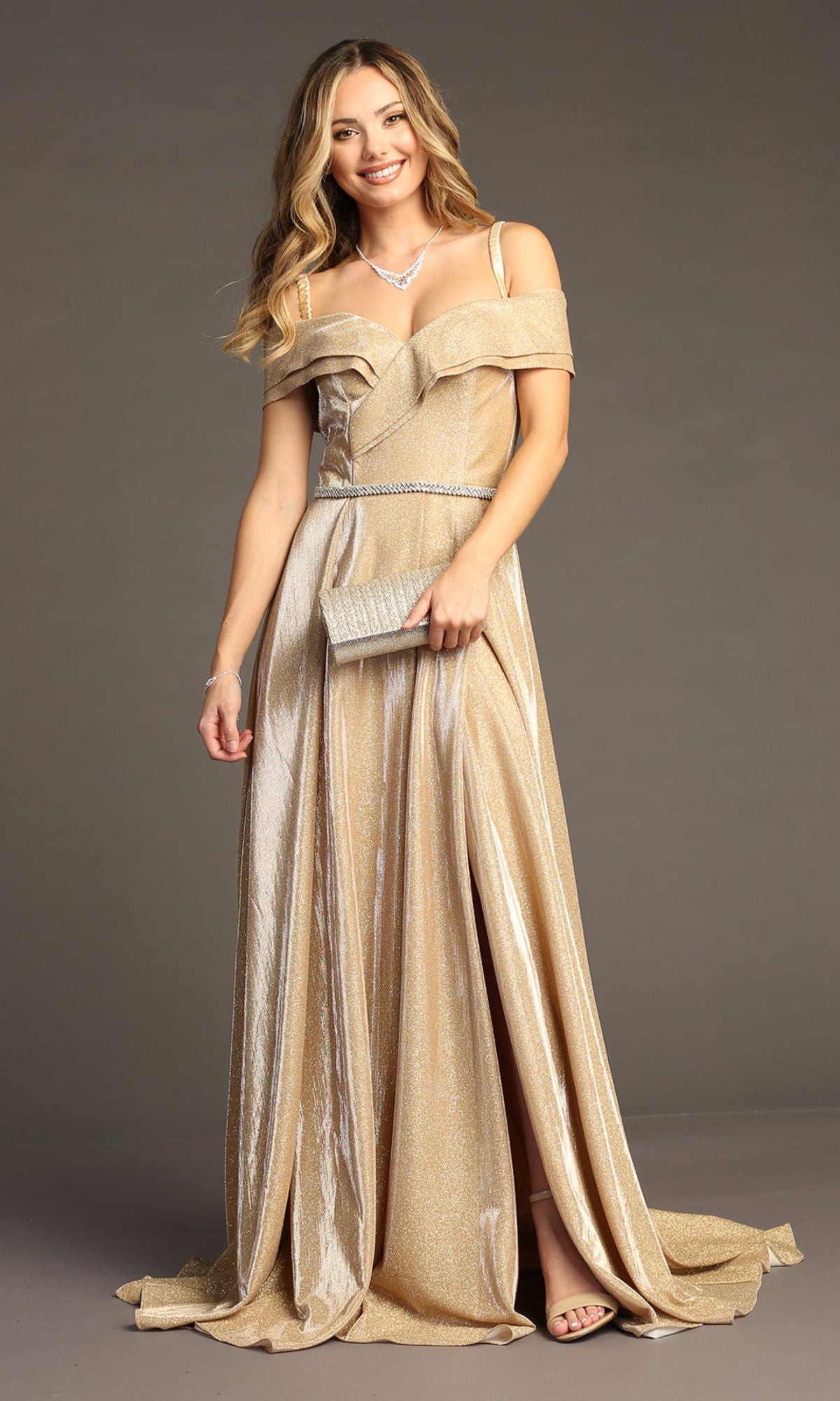 Woman in the Chicas J008 Off-Shoulder Long Glitter Prom Dress, featuring a shimmering gold iridescent fabric with a slit, accessorized with a matching clutch and necklace, smiling against a plain background.