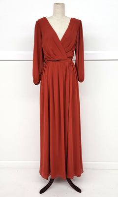 The Chicas J012B is a long-sleeve, floor-length rust red formal dress with a V-neckline and gathered waist, shown on a dress form against a white background.